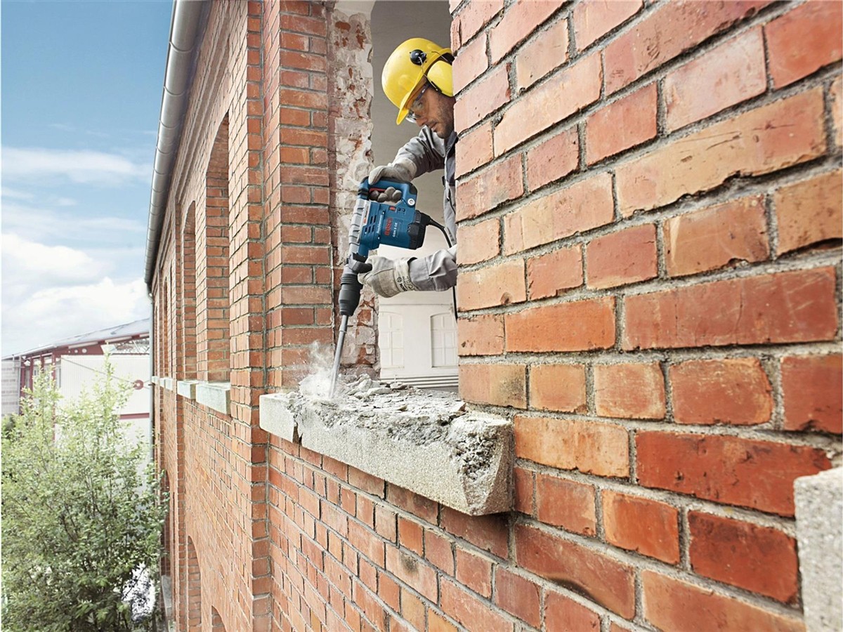 Hammerbohrer, Backsteinmauer, Bauarbeits, Sicherheitshelm, Baustellenarbeiter