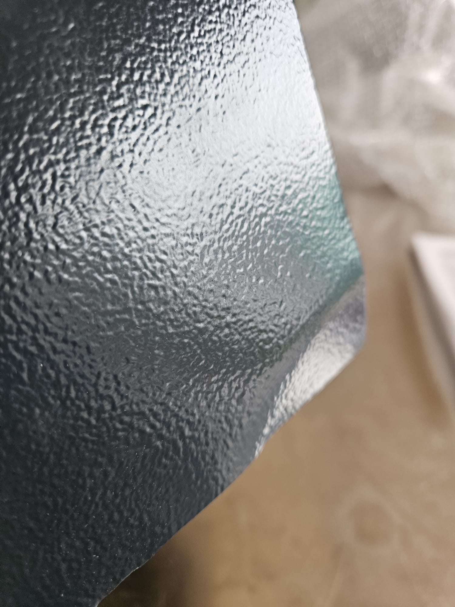 Textured surface, Metallic sheen, Dark gray, Pebbled texture, Curved edge